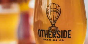 Otherside logo on glass containing beer