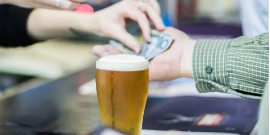 Person paying cash for a beer