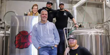 Team members from Akasha and Behmoth in front of brewing equipment