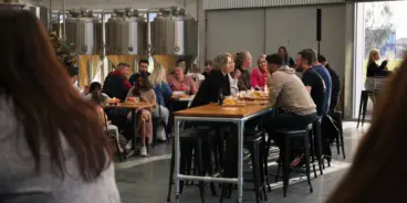 People sitting at tables at Smiley Brewing's venue